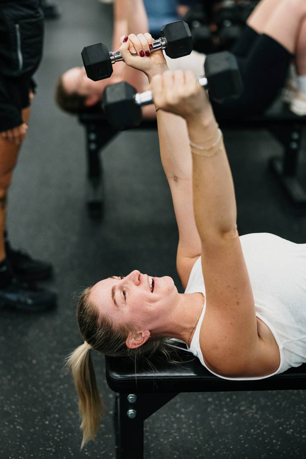 A member smiles mid dumbbell press