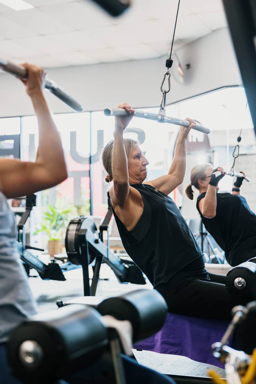An older member presses dumbbells overhead with perfect form